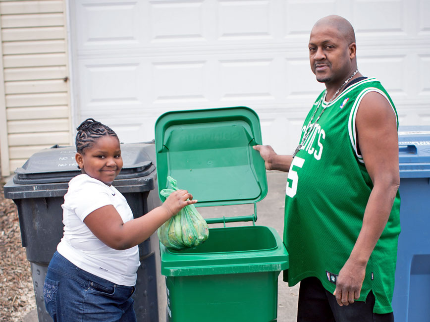 dad and daughter putting organics bin into green organics cart