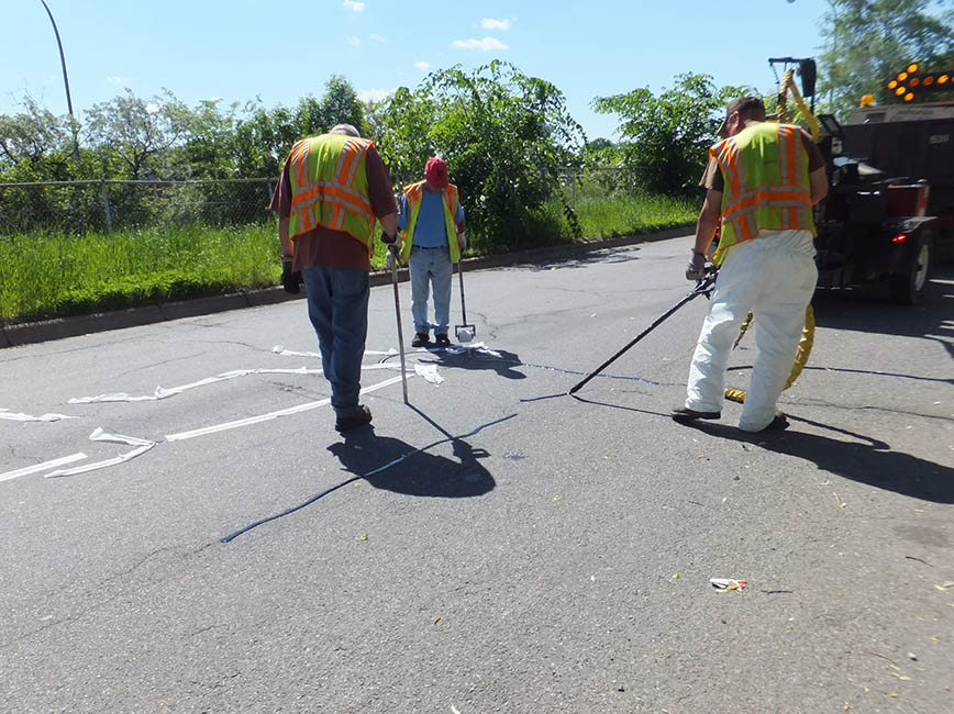 A crew works to seal cracks in the road.