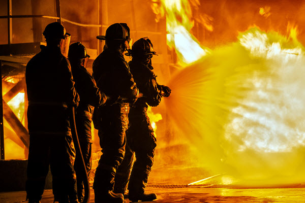Four firefighters spraying water on a fire