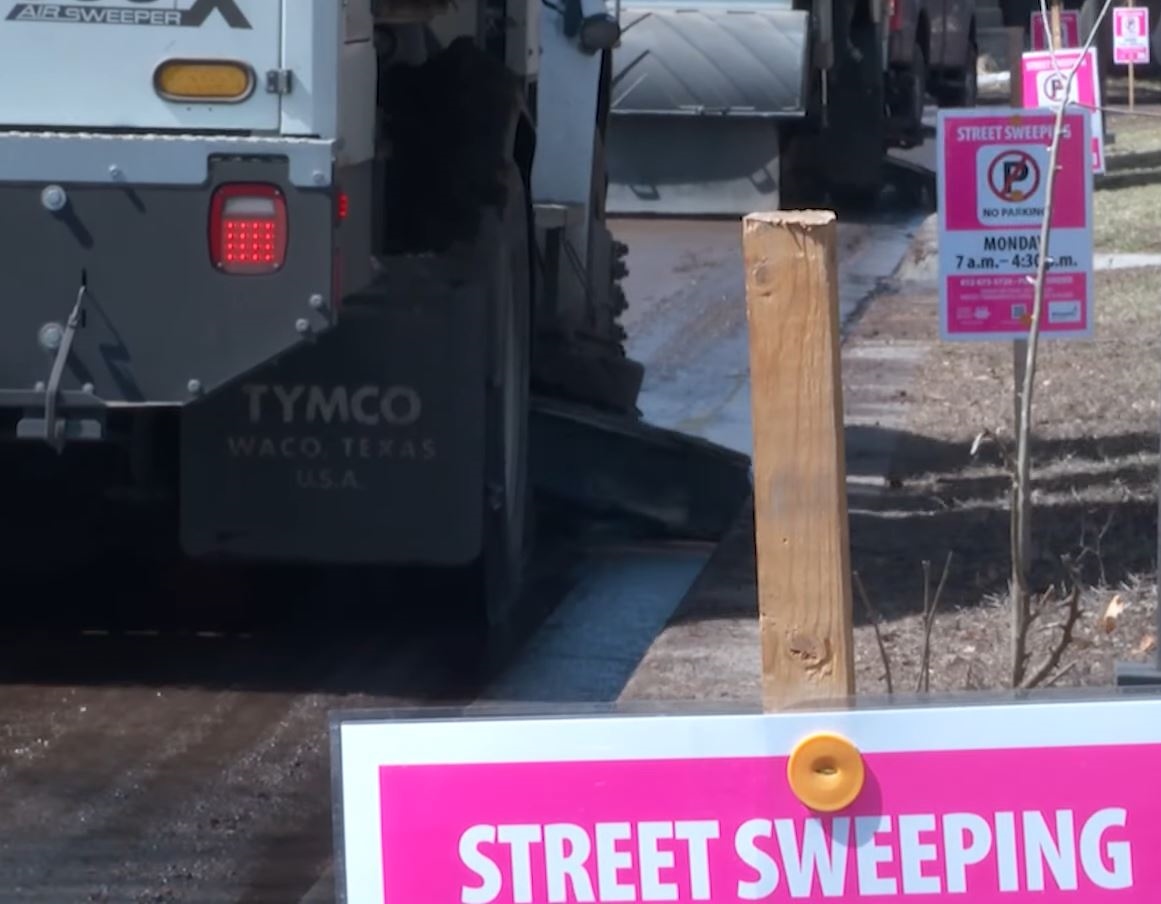 Two examples of the bright pink "Street sweeping - no parking" signs
