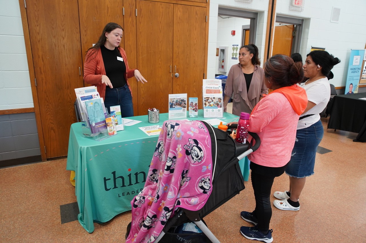 Person behind a table with a green tablecloth, sharing information