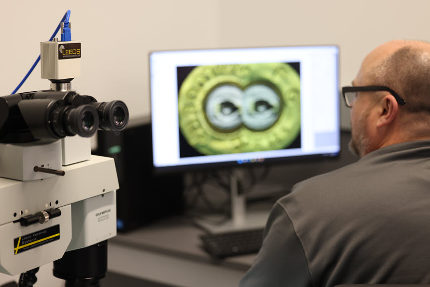 Forensic scientist examining a bullet on a screen