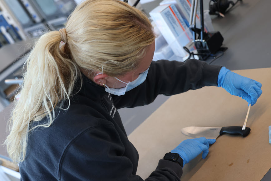 Forensic scientist swabbing a knife