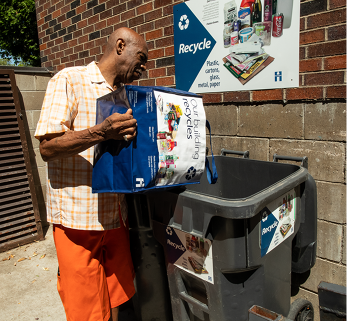 person dumping recycling into a recycling cart an an apartment building person dumping recycling into a recycling cart an an apartment building