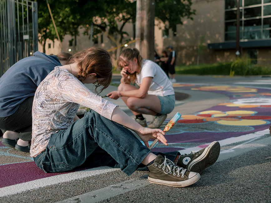 Youth painting murals on asphalt pavement