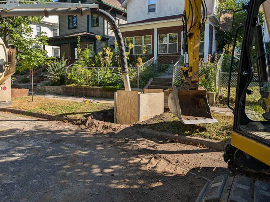 Workers replace a water service line in front of a residence.