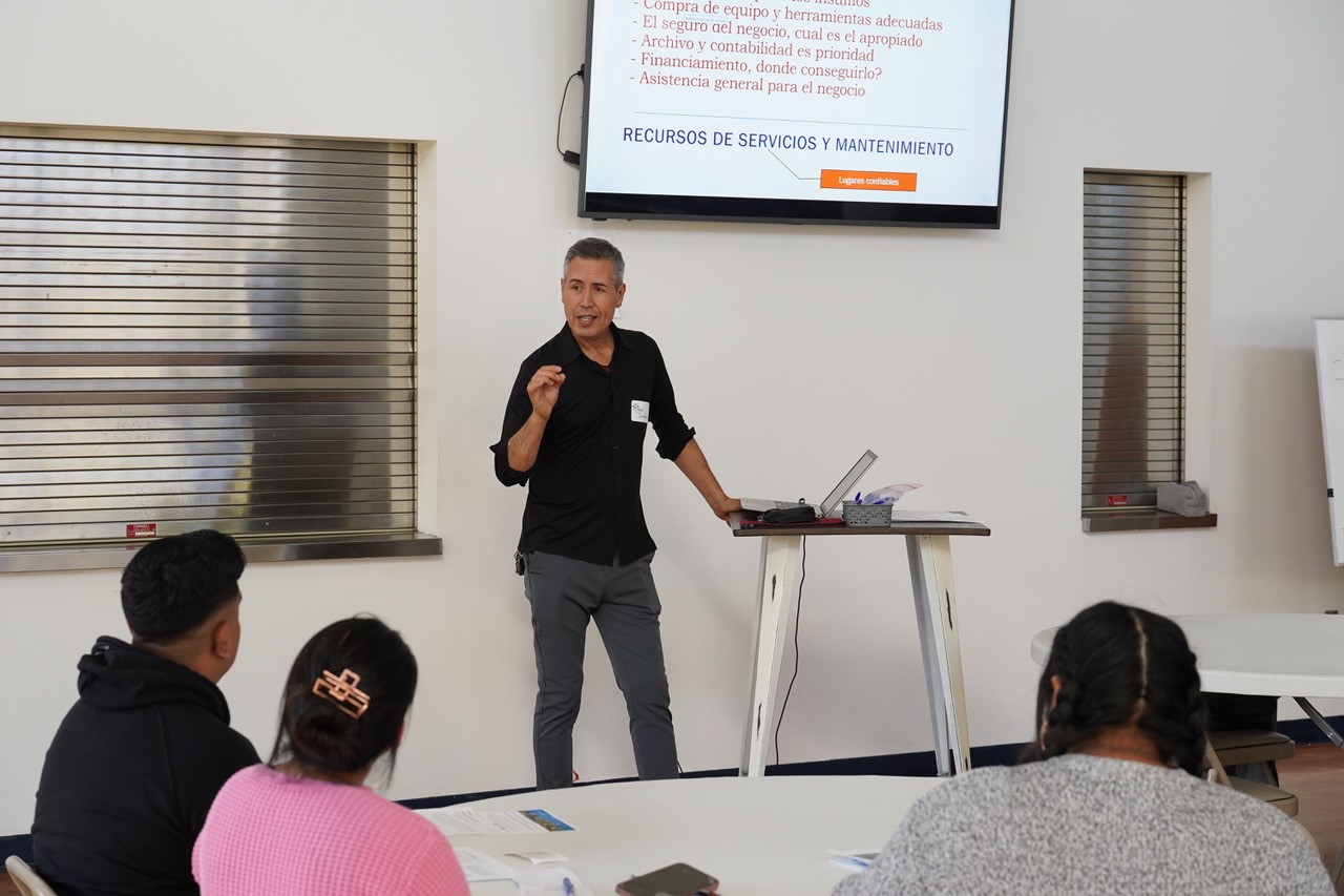 Person standing in front of a large screen, leading a workshop