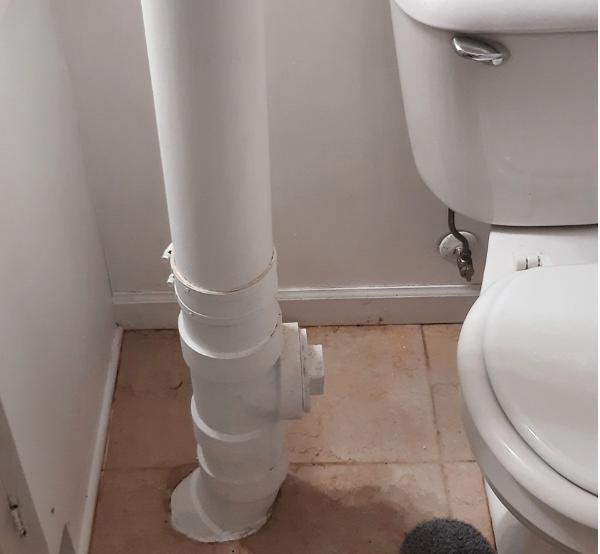 White vertical pipe between toilet and wall