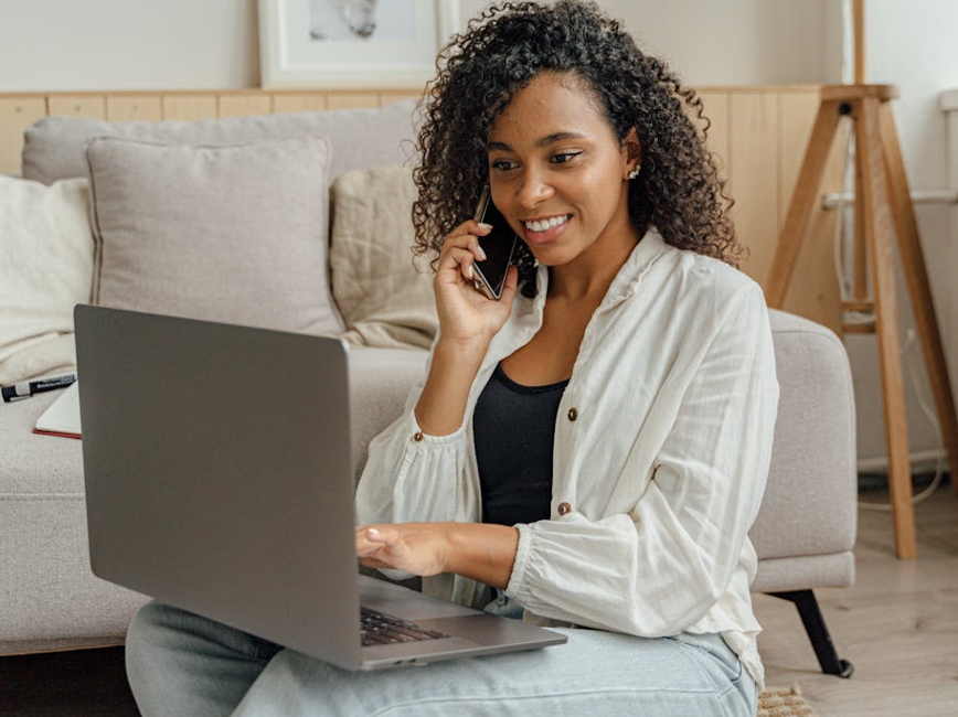 Person talking on phone while using laptop