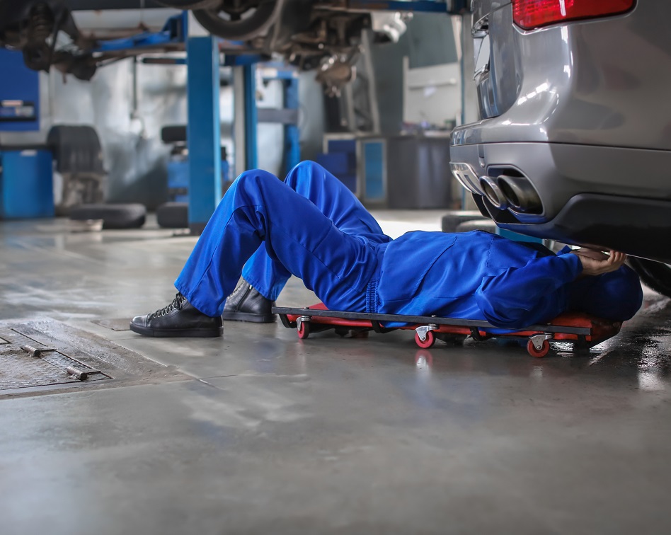 Mechanic working on car with floor drain nearby