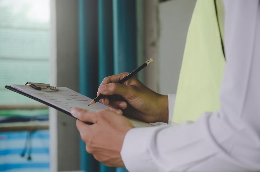 Hands of person holding pencil and clipboard