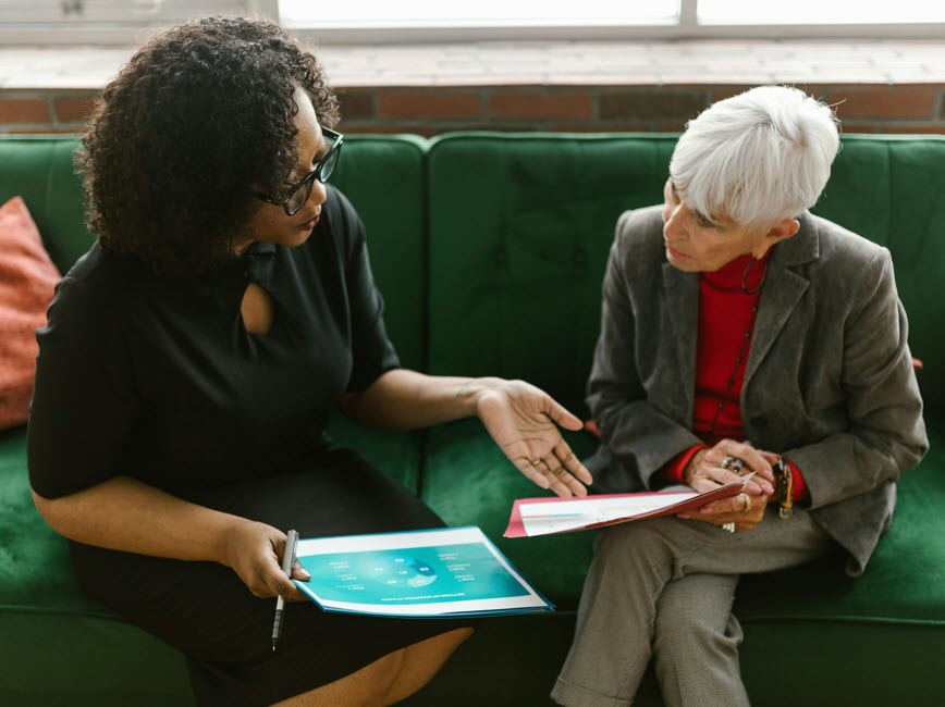 Two people seated while reviewing paperwork