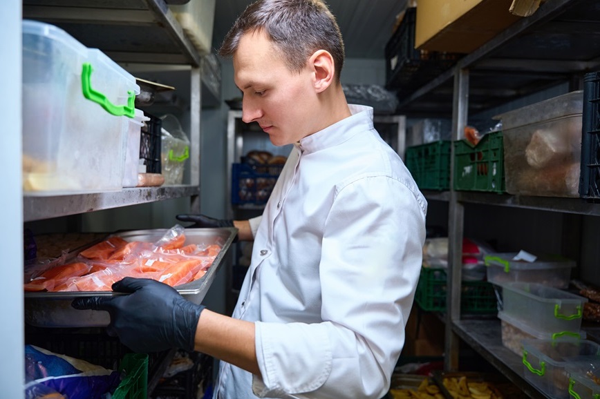 Restaurant employee putting raw meat in cooler