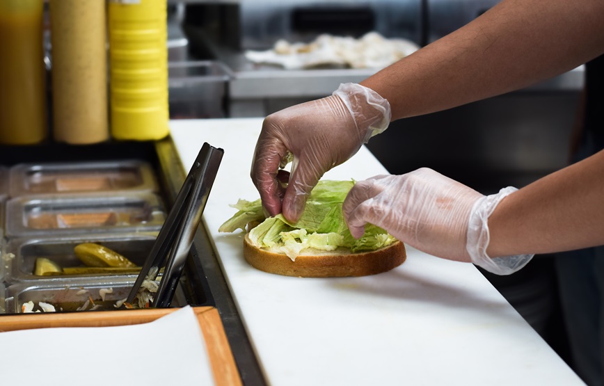 Restaurant worker preparing food while wearing kitchen gloves