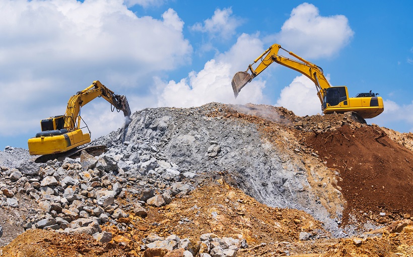 Two excavators on top of rock pile