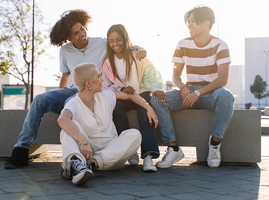 Four teenagers smiling together outside