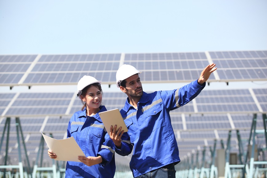 Teenager and adult working in front of solar panels