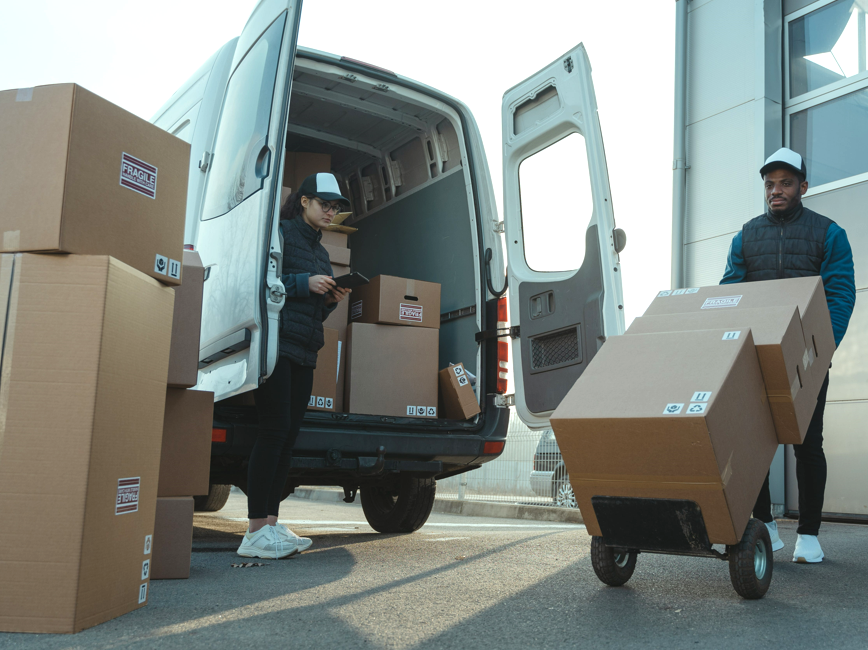 Two people unloading boxes from a delivery van