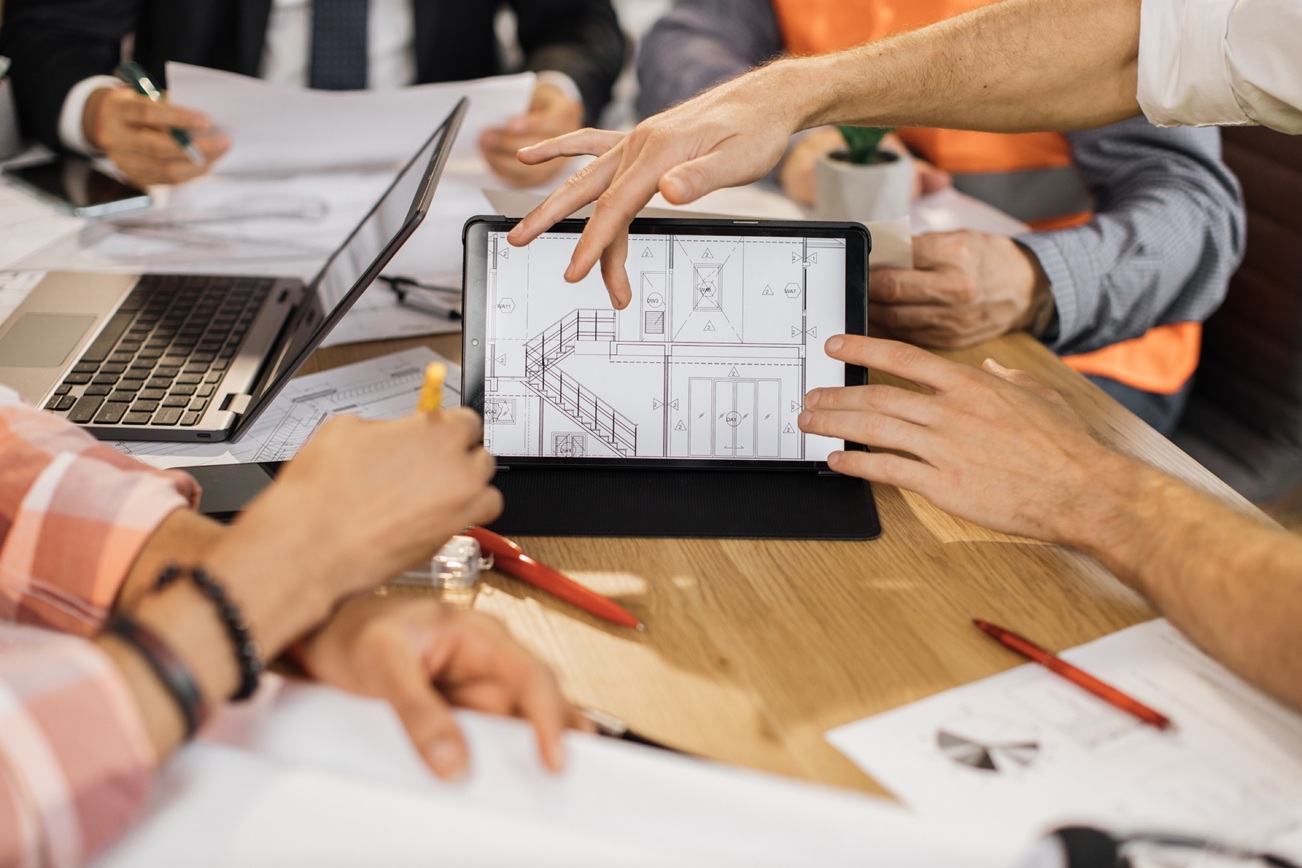 Many hands reviewing blueprints on a tablet Many hands reviewing blueprints on a tablet