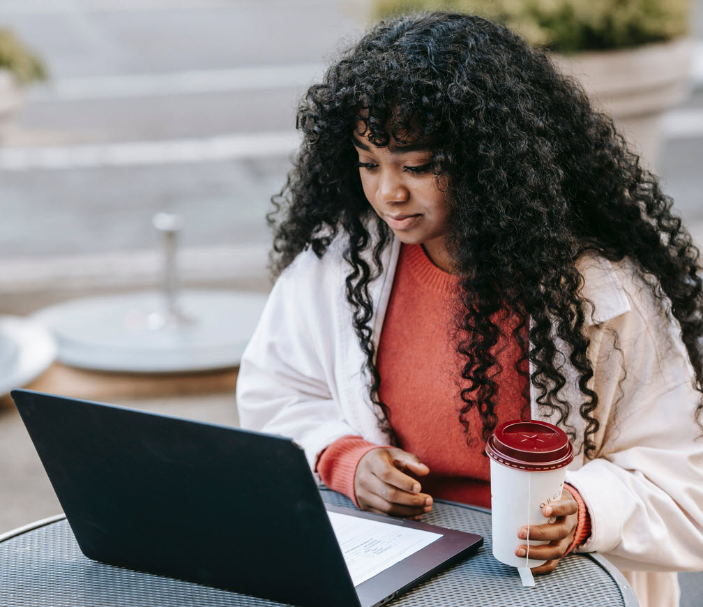 person sits at cafe patio with laptop